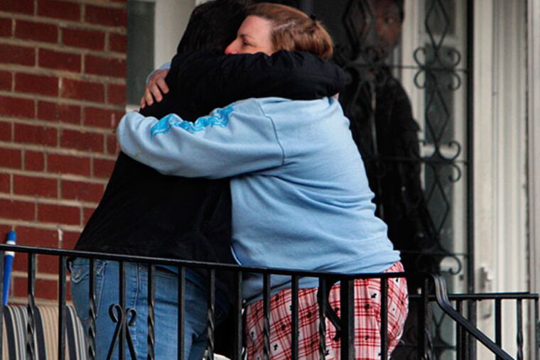Two neighbors hug after two people were found shot to death as police gather on the 300 block of Stevens Street in the Crescentville section of Philadelphia on Sunday Jan. 19, 2013. (Joseph Kaczmarek/For the Daily News)