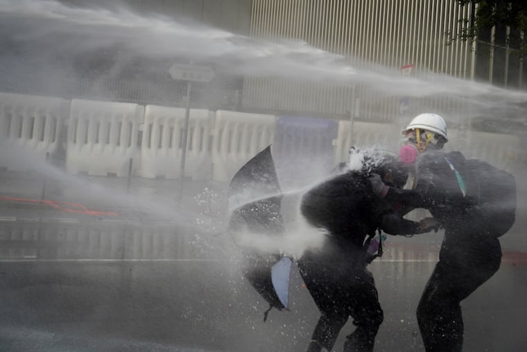 Anti-government protesters are sprayed with water cannon during a demonstration near Central Government Complex in Hong Kong, Sunday, Sept. 15, 2019. Police fired a water cannon and tear gas at protesters who lobbed Molotov cocktails outside the Hong Kong government office complex Sunday, as violence flared anew after thousands of pro-democracy supporters marched through downtown in defiance of a police ban. (AP Photo/Vincent Yu)