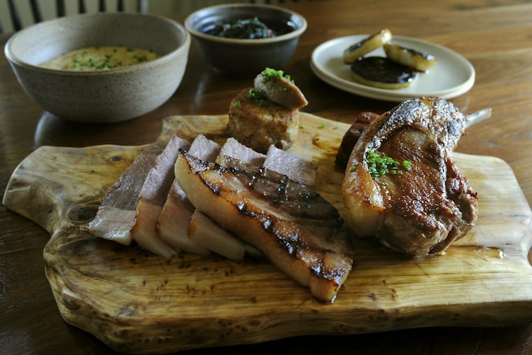 The roast pork platter (chops, shoulder, belly, ham, grits, charred onion, vinegared greens) at the Mainland Inn in Harleysville. (TOM GRALISH/STAFF PHOTOGRAPHER)