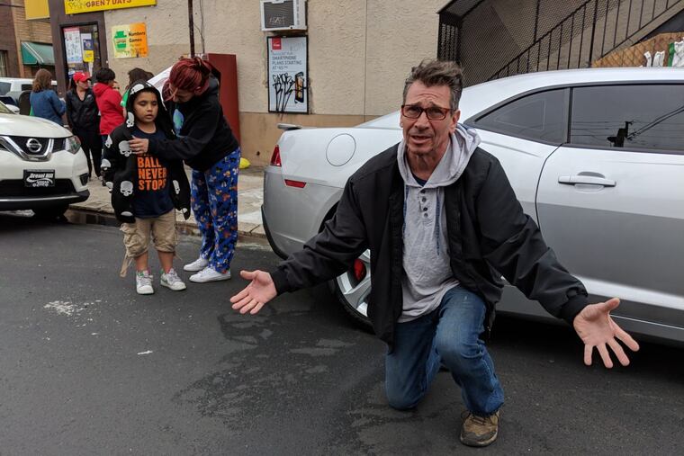 Ralph Schafer kneels over the place on Shunk Street where he found the 11-year-old boy lying on the ground.