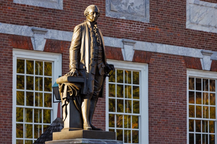 A statue of George Washington stands in front of Independence Hall as the sun rises over Philadelphia. Two hundred and fifty years after its founding, the land of opportunity is failing many Americans, writes the Editorial Board.