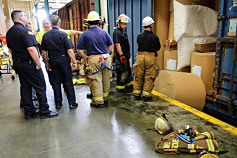 Police and rescue workers look at the boxcar from which two rolls of paper toppled at the Schuylkill Printing Plant, with one of them killing a worker.