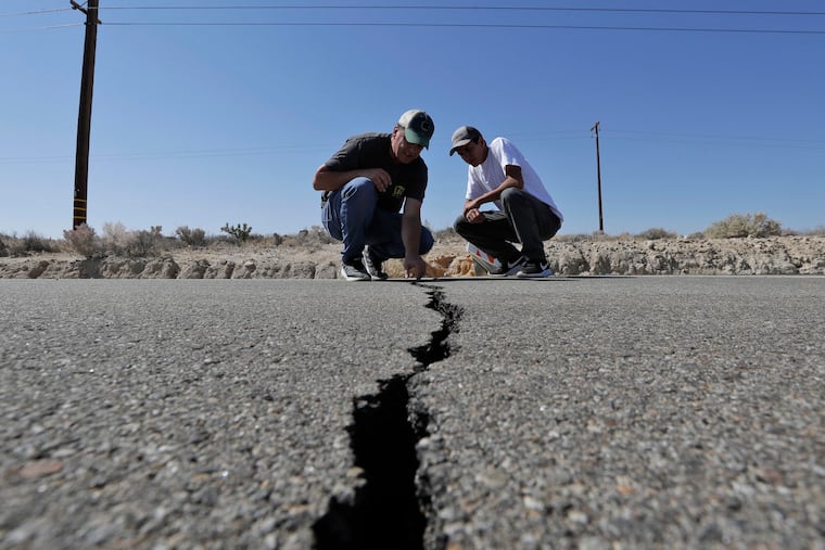 Ron Mikulaco, left, and his nephew, Brad Fernandez, examine a crack caused by an earthquake on highway 178 Saturday, July 6, 2019, outside of Ridgecrest, Calif. Crews in Southern California assessed damage to cracked and burned buildings, broken roads, leaking water and gas lines and other infrastructure Saturday after the largest earthquake the region has seen in nearly 20 years jolted an area from Sacramento to Las Vegas to Mexico.