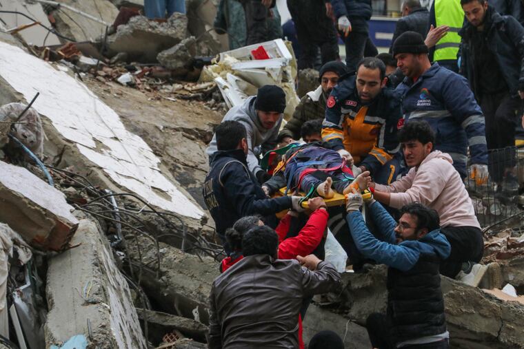 People and emergency teams rescue a person on a stretcher from a collapsed building in Adana, Turkey, on Monday.