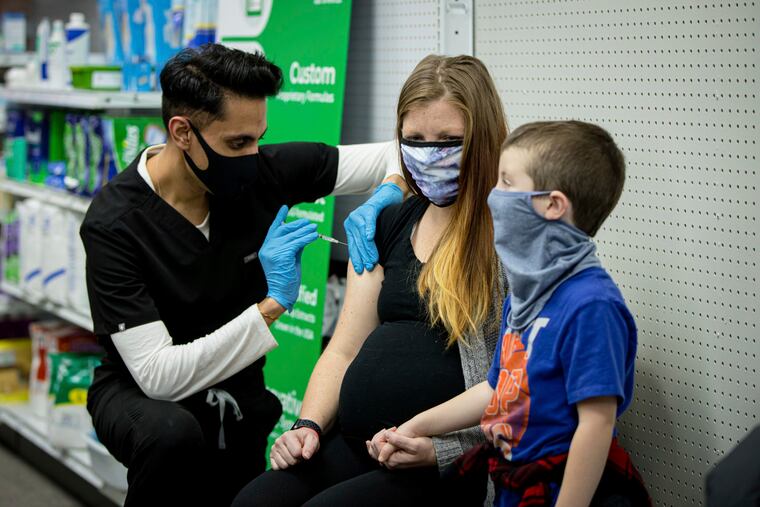Skippack Pharmacy owner and pharmacist Dr. Mayank Amin administers a vaccine to Aubrie Cusumano while son Luca waits in 2021 in Skippack. Amin said that few patients have discussed recent changes in CDC vaccine recommendations. (Chorus Media Group via AP)