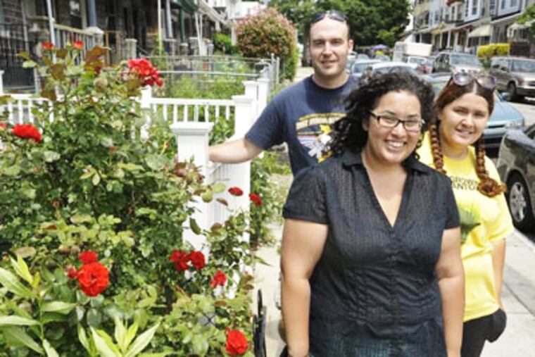 Volunteer Matt Wysong and community avtivists Emaleigh and Aine Doley stand along Rockland St. in Germantiown where the Dolye sisters organized an all-day clean up and flower planting. (RON TARVER / Staff Photographer )