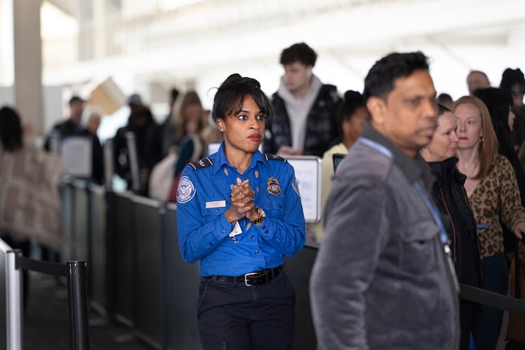 TSA agent Kelly Jonson assists travelers through a busy security line at Gate Section B at Philadelphia International Airport last week.