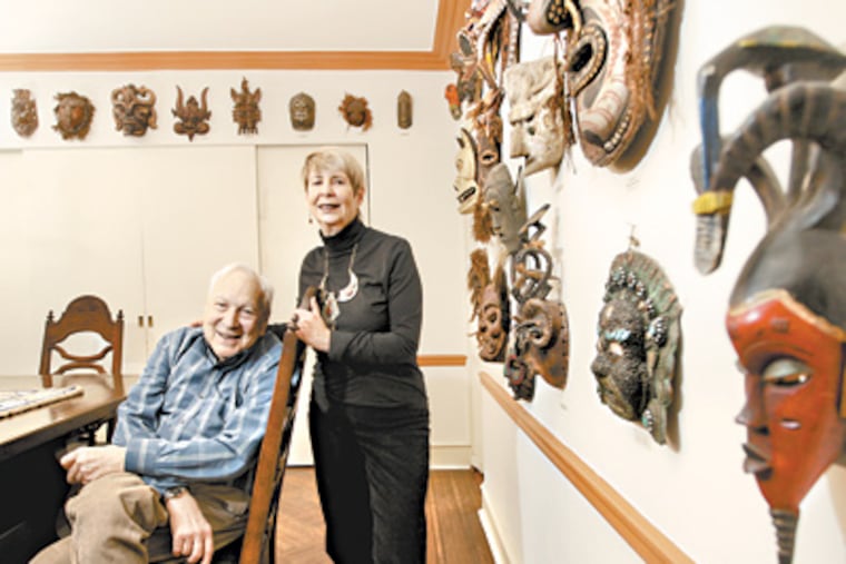 Stanley and Beverly Diamond sitting in the dining room of their home surrounded by tribal masks they have acquired over time in the travels. (Michael Bryant / Staff Photographer)