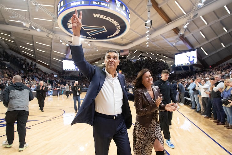 Prior to the game between Villanova and DePaul, Jay Wright gestures to the crowd after being honored for his 21-year career as Wildcats' head coach. He and his wife Patty walk off the court after the ceremony.