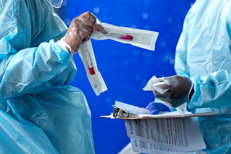 In this July 23 photo, health care workers prepared a COVID-19 test sample before a person self-administered a test at the COVID-19 drive-thru testing center at Miami-Dade County Auditorium in Miami.