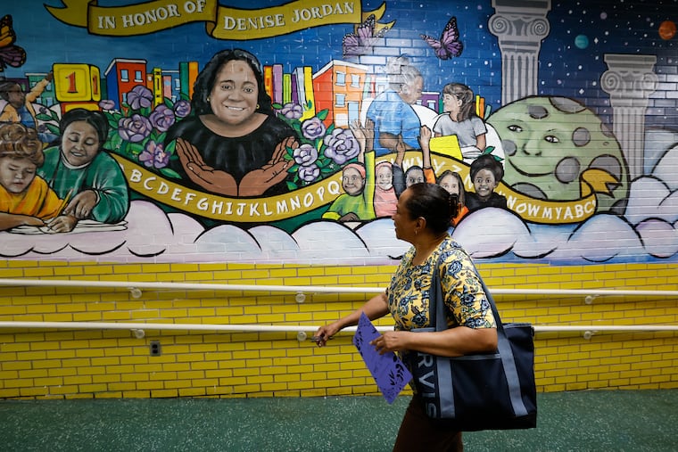 Asuncion Walters looks at the mural of her sister, Denise Jordan, a longtime kindergarten teacher at John Barry Elementary School in West Philadelphia during a kindergarten mural dedication and ceremony on Thursday. Jordan died suddenly at age 53 last summer.