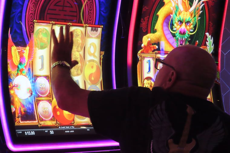 A gambler touches the glass surface of a slot machine at the Hard Rock casino in Atlantic City, N.J., on Aug. 8, 2022.