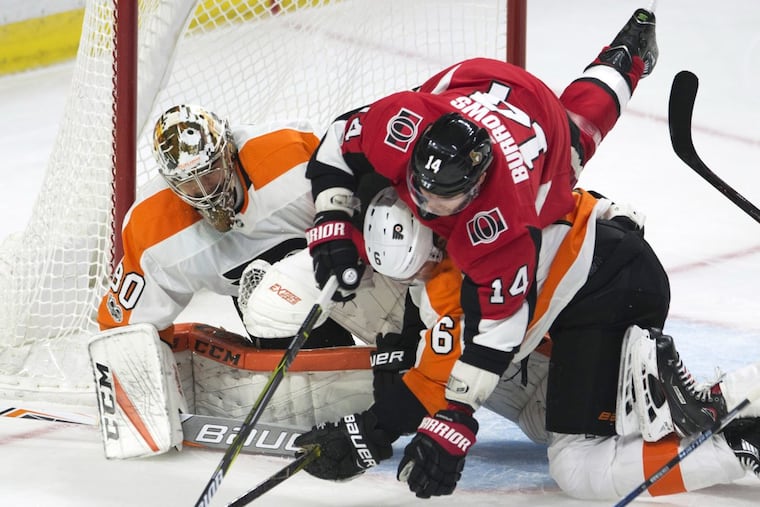Flyers defenseman Travis Sanheim, bottom, and Ottawa Senators right winger Alexandre Burrows battle in front of goalie Michal Neuvirth during the third period Thursday night.