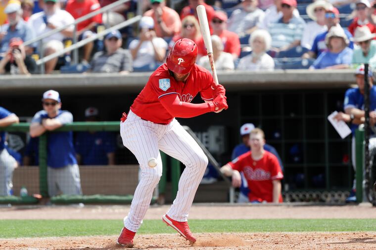 Phillies Bryce Harper looks down at the baseball after getting hit by a pitch in the ankle.