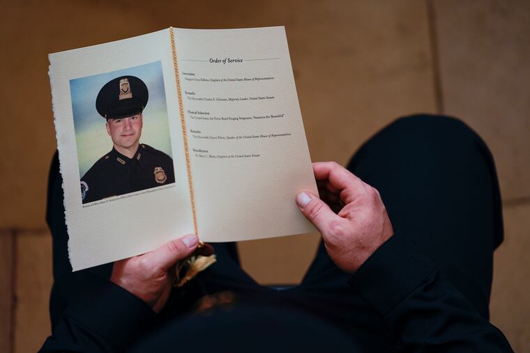 In this Feb. 3 photo, a U.S. Capitol Police officer holds a program during a ceremony memorializing U.S. Capitol Police Officer Brian Sicknick.