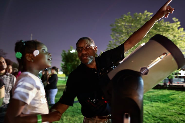 Franklin Institute astronomer Derrick Pitts instructs a young sky watcher at a 2017 "star party." Pitts said that Tuessday night's light show likely results from sunlight animated icy fuel particles ejected from a spacecraft.
