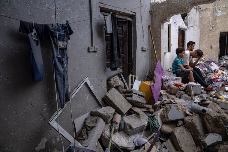 Palestinians sit on the rubble of a house after it was struck by an Israeli airstrike in Khan Younis, southern Gaza Strip, on Sunday, Oct. 29, 2023.