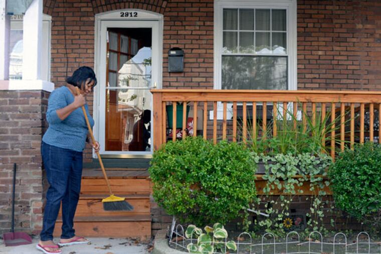 Diane Valentine Bey sweeps outside her home October 7, 2014. Her Sandy-damaged porch was replaced by the Atlantic City Long Term Recovery Group. ( TOM GRALISH / Staff Photographer )