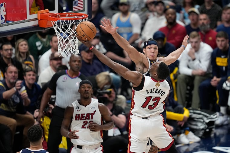 Miami Heat center Bam Adebayo (13) shoots the ball while defended by Denver Nuggets forward Aaron Gordon, rear right, while Jimmy Butler, left, looks on.