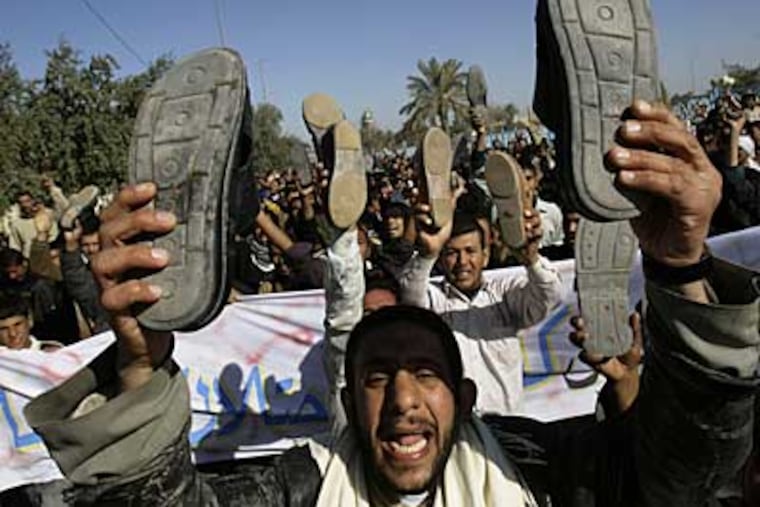 Iraqis raise their shoes as hundreds demanded a release for Iraqi journalist Muntadhar al-Zeidi who threw his shoes at US President George W. Bush in Kufa, Iraq, Friday. Dec. 19, 2008. (AP)