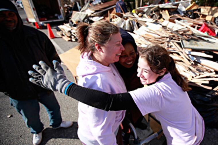 In Atlantic City, Gloria Woody (center), 72, gets a hug from Cindy Rodgers (left) and Jenna Tibbitts, both volunteers from First United Methodist Church in Moorestown. "It’s like God sent me angels to help fix this," Woody said. At left is her son Frank, 48. DAVID SWANSON / Staff Photographer