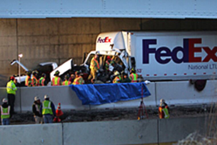 Firefighters remove the body of the driver of a Fed Ex truck that crashed with two other vehicles Friday morning on the PA Turnpike. (David Swanson / Inquirer)