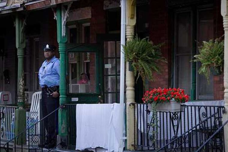 A Philadelphia police officer stands outside a home on the 2500 block of North Spangler Street in Strawberry Mansion, where a couple was found dead overnight (Alejandro Alvarez / Staff)
