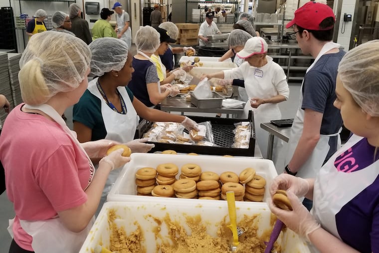 Volunteers at MANNA make sandwiches using whole wheat bagels and hummus.