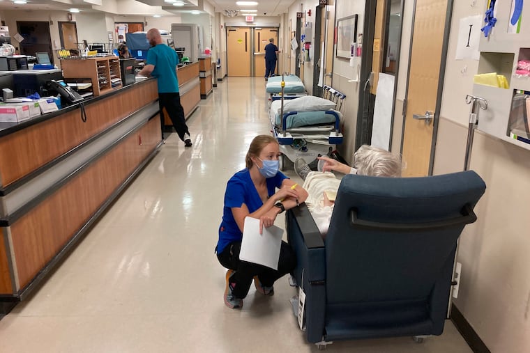 A nurse talks to a patient in the emergency room at Salem Hospital in Salem, Ore., on Aug. 20, 2021. moving patients out of the ER to rooms "upstairs" often no longer means an inpatient room. (AP Photo/Andrew Selsky, File)