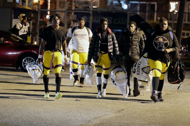 Camden High football players walk back to their field and locker room on Friday night, after their playoff game at Pleasantville was interrupted by gunfire that injured three people.