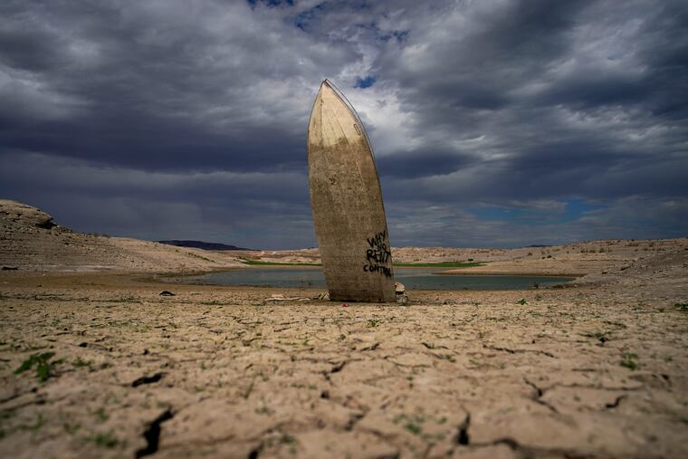 A formerly sunken boat stands upright into the air with its stern buried in the mud along the shoreline of Lake Mead at the Lake Mead National Recreation Area on June 22, 2022, near Boulder City, Nev. The U.S. Interior Department announced, Friday, Oct. 28, 2022, that it will consider revising a set of guidelines for operating two major dams on the Colorado River in the first sign of what could lead to federal action to protect the shrinking reservoirs behind them.