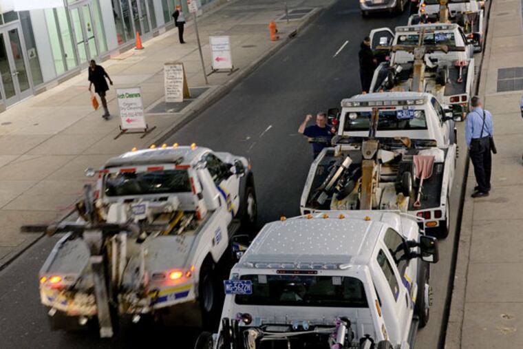 Trucks line up on 8th Street near Arch on Monday to begin towing. (TOM GRALISH/STAFF PHOTOGRAPHER)