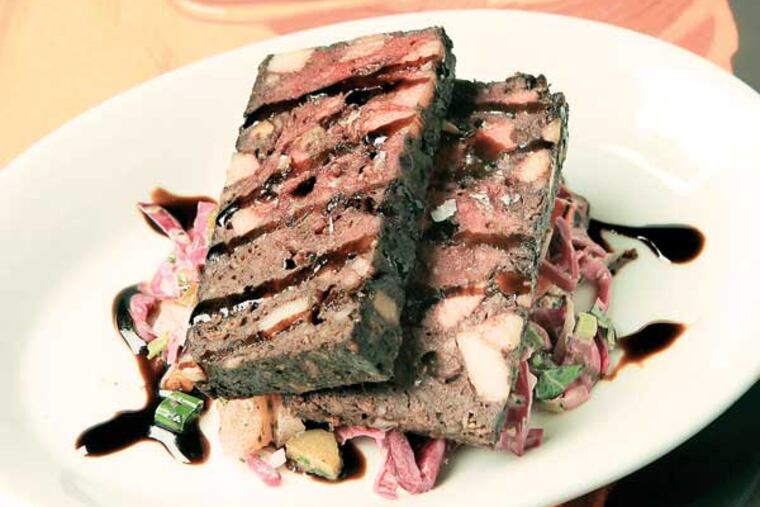The cherry, pecan sausage is shown on top of one of the many pig-related pictures and curios that decorate Cochon, 801 E. Passyunk Ave. ( CHARLES FOX / Staff Photographer )