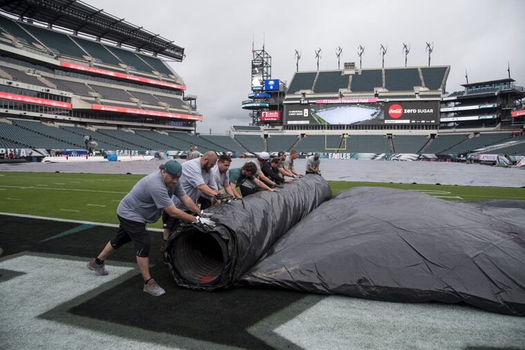 Members of the Eagles grounds crew roll up the tarp protecting the field from rain October 8, 2017 getting ready for the game against the Arizona Cardinals. CLEM MURRAY / Staff Photographer