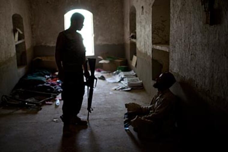 An Afghan soldier stands guard next to a villager who was detained at COP Nolen due to trace amounts of ammonium nitrate found on his fingers in Kandahar, Afghanistan on July 25. (AP Photo/Rodrigo Abd)
