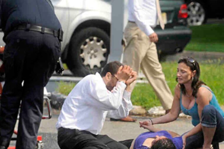 A Cherry Hill rescue crew arrives at the hit-and-run scene along Route 70 as nursing student Desiree Forbes (right) and Michael Medina comfort Binh Tsan, 25, of Runnemede. (Tom Gralish / Staff Photographer)