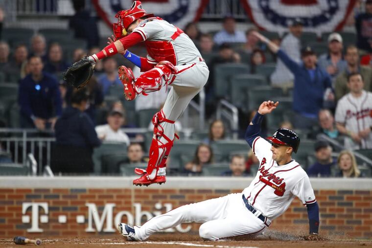 Atlanta’s Ryan Flaherty sliding under Phillies catcher Andrew Knapp (15) to score in the third inning Friday.