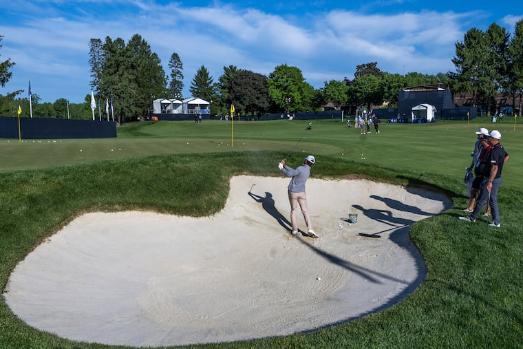 Michael Brennan hits from a sand trap on Monday during a practice round ahead of the PGA Championship at Aronimink Golf Club in Newtown Square.