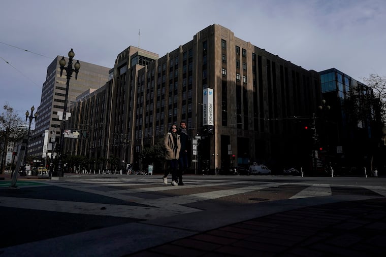 People cross the street in front of Twitter headquarters in San Francisco on Friday.