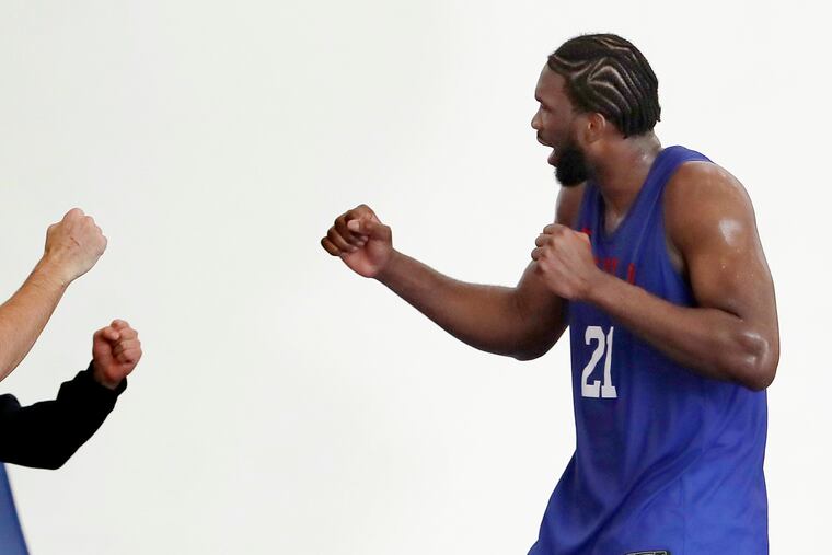 Sixers Joel Embiid taps fists with members of the coaching staff during training camp on Oct. 4.