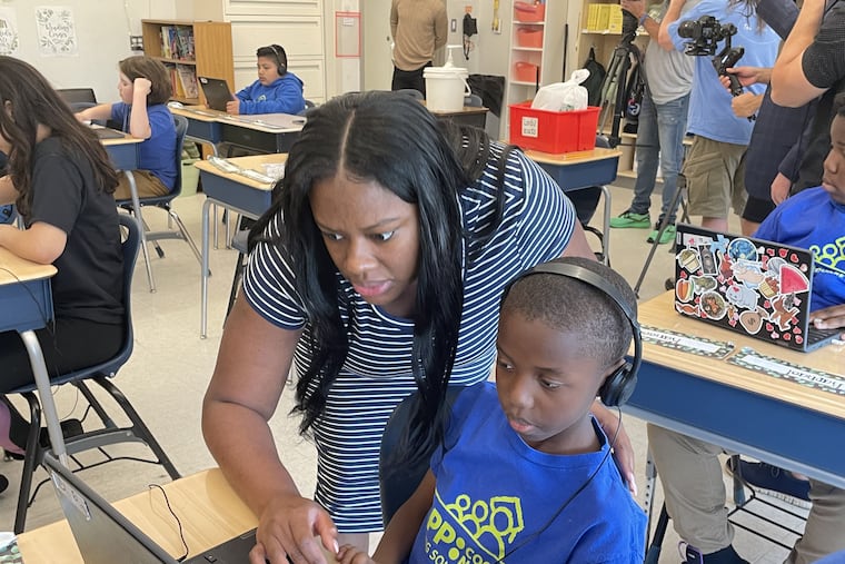 Erica Nelms, an elementary school teacher at KIPP Lanning Square Primary in Camden, helps a student moments before she received a $5,000 RISE award from the Camden Education Fund. She was cited for improving students' reading scores.