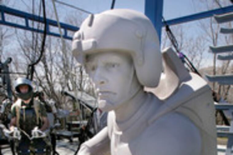 Software engineer Rex Jameson, wearing a robotic soldier suit being made for the U.S. Army, stands next to a mock-up statue of a future soldier in Salt Lake City, Utah.