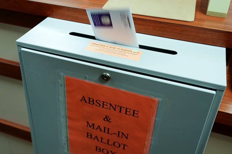 A ballot is deposited into a box at the county clerk's office in Erie. A newly approved resolution is meant to bar groups of people openly carrying firearms from gathering near polling places and drop boxes.