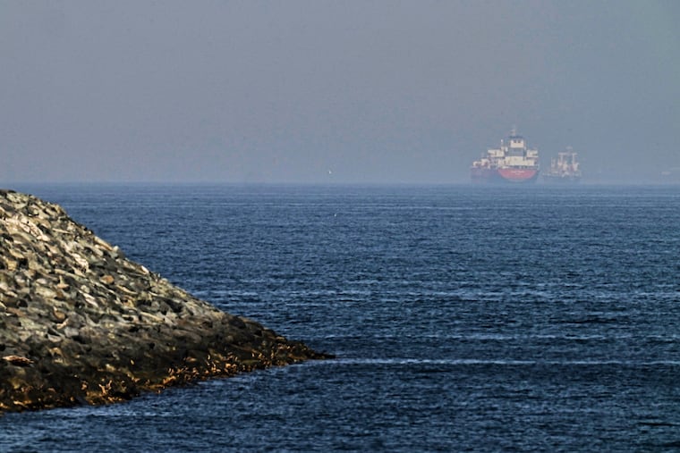 Cargo ships are seen at sea near the Strait of Hormuz, as viewed from a rocky shoreline near Khor Fakkan, United Arab Emirates, Friday, May 1, 2026.