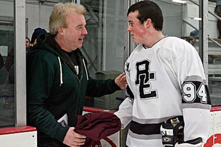 Nevin O'Kane hands a hockey blanket, made by the Gloucester Catholic players, to his dad, Bill O'Kane. (Akira Suwa/Staff Photo)