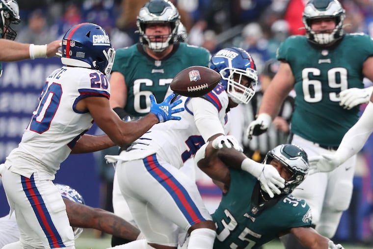 New York Giants cornerback Julian Love (left) grabs the ball after Philadelphia Eagles running back Boston Scott (right) fumbles in the fourth quarter. The Eagles lose 13-7 to the Giants at MetLife Stadium in East Rutherford, New Jersey on Sunday, Nov. 28, 2021.