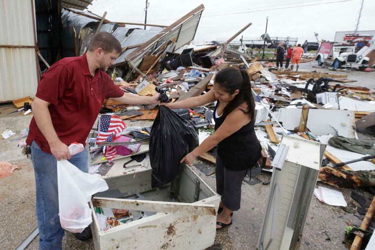 Kenneth Bryant and his wife, Jennifer , search through debris from their business, Bryant's Auto Sales, in Katy, Texas, looking for car keys and paperwork. Houston Chronicle