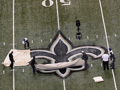 Workers pull a tarp off the the fleur de lis, the New Orleans Saints logo, before an NFL football game between the New Orleans Saints and the Philadelphia Eagles at the Mercedes-Benz Superdome in New Orleans, Monday, Nov. 5, 2012. (AP Photo/Bill Feig)