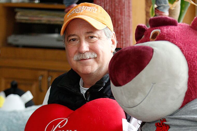 Bob Goodman sits next to a large stuffed animal with a shirts made by his daughter saying “I love Bob” and holds a heart shaped pillow he received from University of Pennsylvania Hospital in his Mt. Holly home. ( AKIRA SUWA / Staff Photographer )