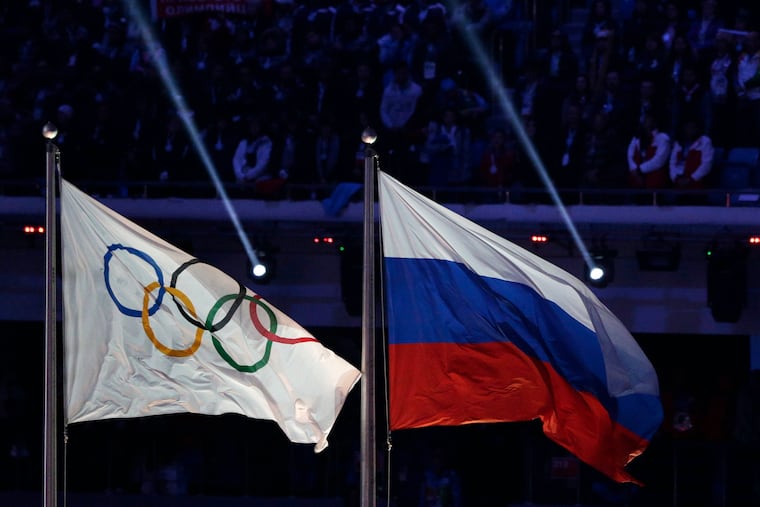 The Russian national flag (right) flying after it was hoisted next to the Olympic flag during the closing ceremony of the 2014 Winter Olympics in Sochi, Russia.